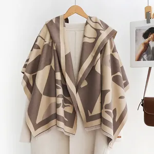Detail van gebreide poncho met capuchon, abstract bladmotief en decoratieve franjes