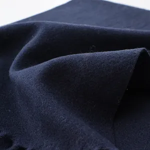 Detailed close-up showing the soft wool texture and fringe of the navy blue scarf