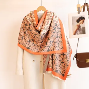 Detail of paisley pashmina scarf texture with tassels layered on beige wool coat