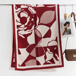 Detailweergave van rood-witte gebreide bloemensjaal met elegante franjes aan een metalen stang