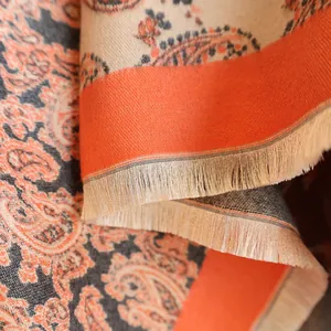 Close-up of paisley pattern cashmere-like scarf with warm orange tones and fringe trim