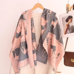 Détail de l'étiquette en cuir fait main sur l'écharpe rose et grise à motif de chevaux