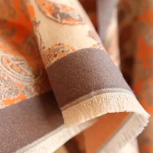 Macro view of paisley printed cashmere-like scarf showing soft texture and fringe edges