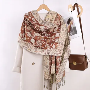 Dettaglio di sciarpa paisley vintage con frange su un cappotto di lana beige