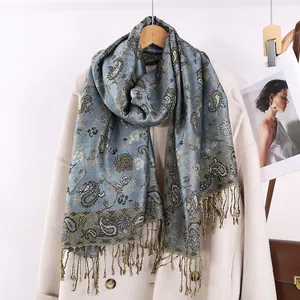 Sciarpa blu con motivo floreale paisley e nappe appesa su un cappotto beige