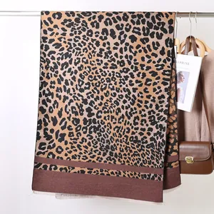 Detail of leopard print faux cashmere scarf featuring a color block hem and fringe edges