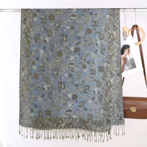 Dettaglio della sciarpa pashmina blu grigiastro con motivi paisley e frange morbide