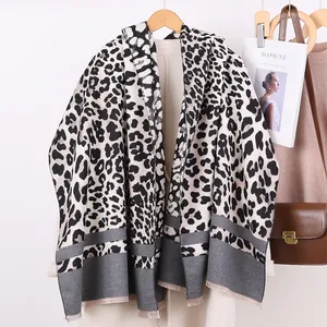Elegant leopard print cashmere-feel scarf with stripes and tassels on a beige coat