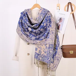Dettaglio della sciarpa jacquard paisley blu e beige con nappe decorative su cappotto di lana