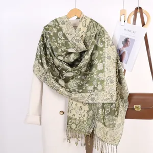 Dettaglio di scialle jacquard paisley verde con frange su cappotto e borsa