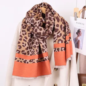 Detail of leopard print scarf with orange color block edge and soft fringe texture