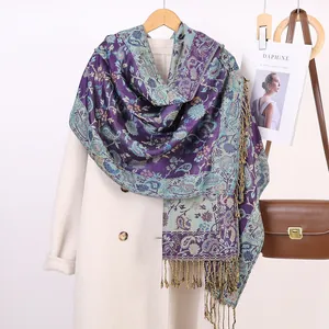 Dettaglio dello scialle vintage con motivo paisley e frange su un cappotto bianco