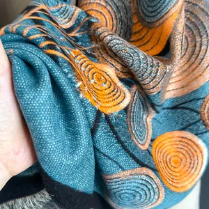 Detail eines Ölgemälde-Schals mit orangen Spiralmustern und schwarzen Quasten-Details