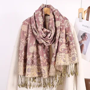 Dettaglio di sciarpa con motivo Paisley rosso vintage e frange su un cappotto bianco