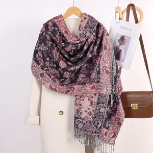 Dettaglio di sciarpa jacquard vintage con motivo paisley e nappe su un cappotto bianco
