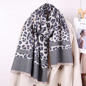 Detail of grey leopard print scarf with soft tassels on a wool coat display