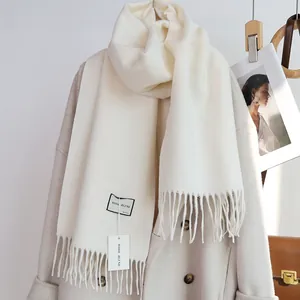 Details der weichen Wollmischung und der eleganten Fransen an einem cremeweißen Winterschal