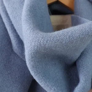 Makroaufnahme der Textur von blauem Wollstoff mit weichen Fransen und warmem Webdetail
