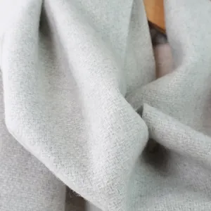 Nahaufnahme eines hellgrauen Wollschals mit weicher Köperbindung und gebürsteter Textur