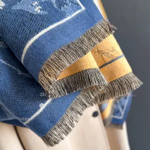 Detailed close-up of thick knitted scarf with navy and yellow jacquard and grey tassels
