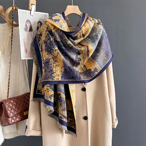Artistic oil painting style cashmere scarf with gold prints and fringes on a tan coat