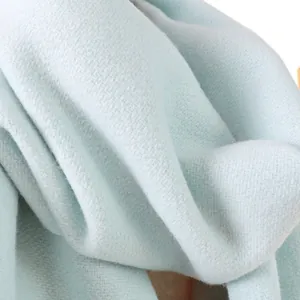 Detailaufnahme der weichen Wollstofftextur eines mintblauen Winterschals