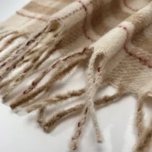 Close-up of beige plaid wool scarf featuring soft fringe and detailed woven texture