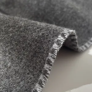 Macro shot of dark grey wool fabric showing soft texture and neat stitching on edges