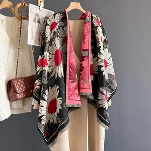 Close-up of floral cashmere scarf with daisy patterns and fringe on beige coat