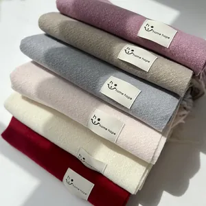 Dettaglio di sciarpe colorate effetto cashmere con etichette logo in pelle home hope