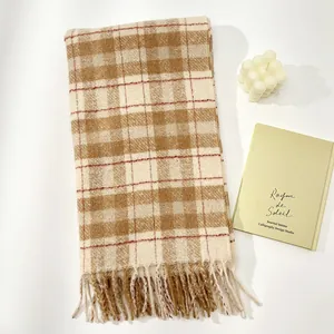 Close-up of thick plaid wool scarf with fringe tassels beside a white bubble candle