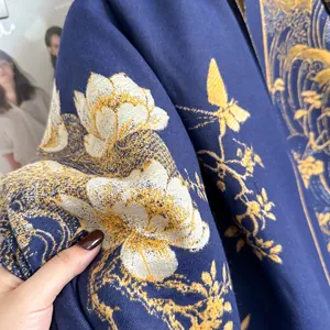 Dettaglio ravvicinato della sciarpa blu scuro effetto cashmere con fiori e farfalle dorate