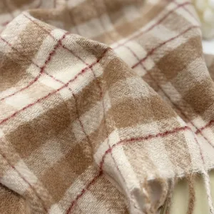 Close-up of thick wool plaid scarf texture with soft tassels and brown check pattern