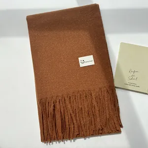 Dettaglio della sciarpa caramello con nappe, trama in finto cashmere ed etichetta tessuta