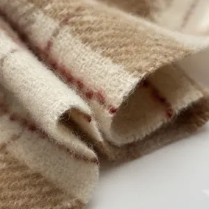 Macro texture of soft wool plaid scarf featuring beige and brown check with red lines