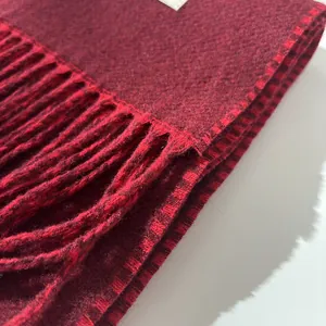 Close-up of luxury burgundy wool scarf with soft fringed edges and premium texture