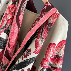 Close-up of thick beige cashmere-feel scarf featuring vibrant red floral print detail