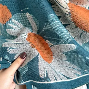 Detailed view of teal cashmere-like scarf showing thick knit daisy jacquard texture