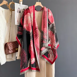 Thick knit winter shawl with red abstract circles and fringe over a beige wool coat