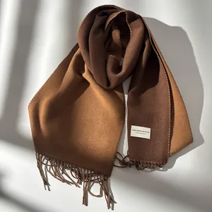 Elegant two-tone wool scarf in brown and camel with fringes and natural sunlight shadows