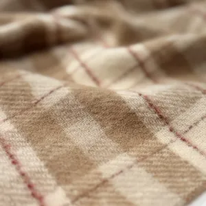Detailed close-up of thick plaid wool scarf fabric with soft tassels and warm texture