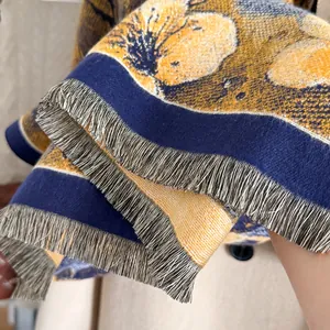 Detailed view of yellow floral pattern and silver-grey tassels on cashmere scarf