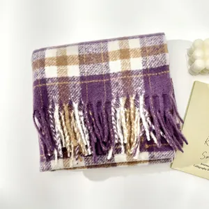 Detail of purple and beige plaid wool scarf featuring long fringes on white background