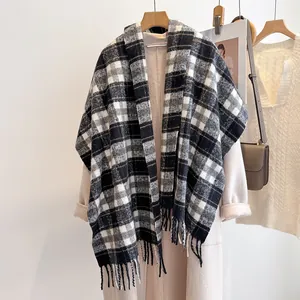 Detailed view of black and white plaid wool scarf with soft tassels on beige coat