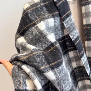 Close-up of thick plaid wool scarf showing soft texture and detailed black white pattern
