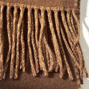 Close-up of premium wool scarf fabric texture with detailed twisted tassel fringes