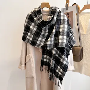 Close-up of black and white plaid wool scarf with long tassels worn on a beige coat