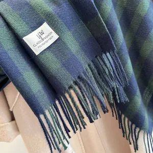 Close-up of blue and green plaid polyester scarf with fringe on a wool coat