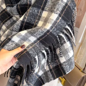 Macro detail of plaid wool scarf featuring classic tassels and soft luxury texture