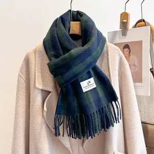 Detail of blue and green plaid polyester scarf with fringe on a beige coat